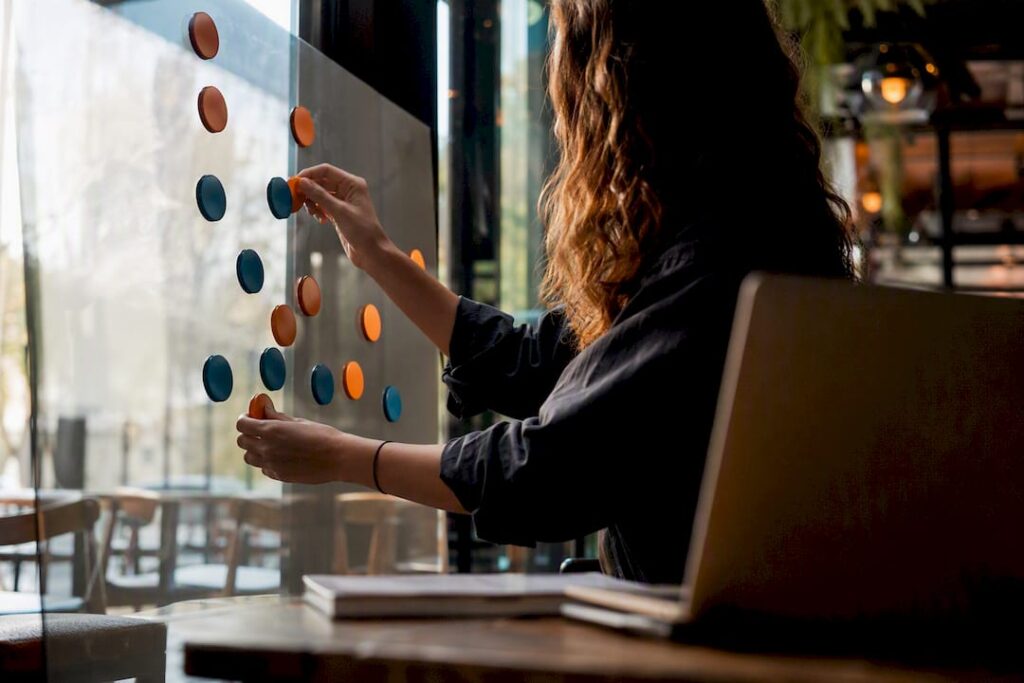 Hands arranging marketing strategy magnets on glass board